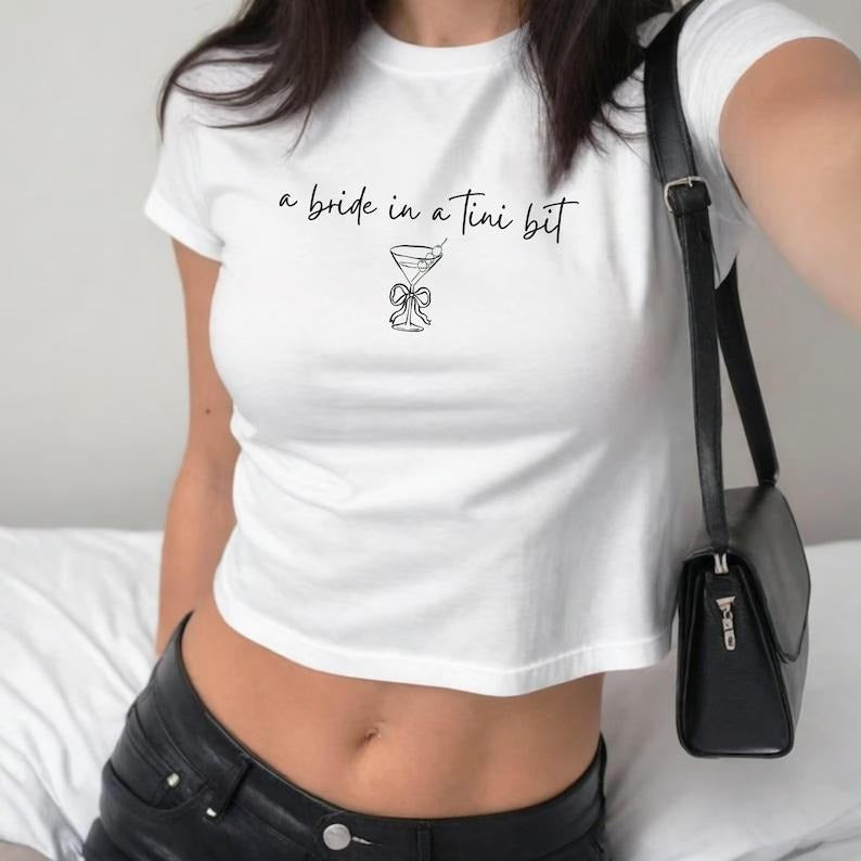 A Bride in a Tini Bit Womens Baby Tee, Bachelorette Shirt for Bride, Cute Martini Bride Top, Y2K Bridal Shower Apparel,...